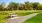 A bench on the grounds of our 55 and over community in Princeton, featuring a path through the lawn and trees.