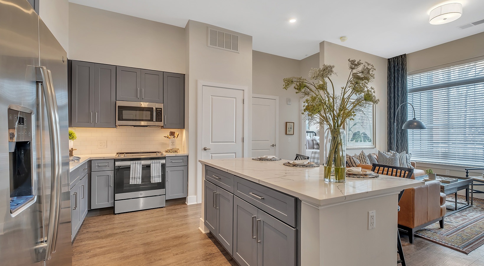Island Kitchen Model kitchen at our active adult apartments, featuring stainless steel appliances and a kitchen island with marble counters.