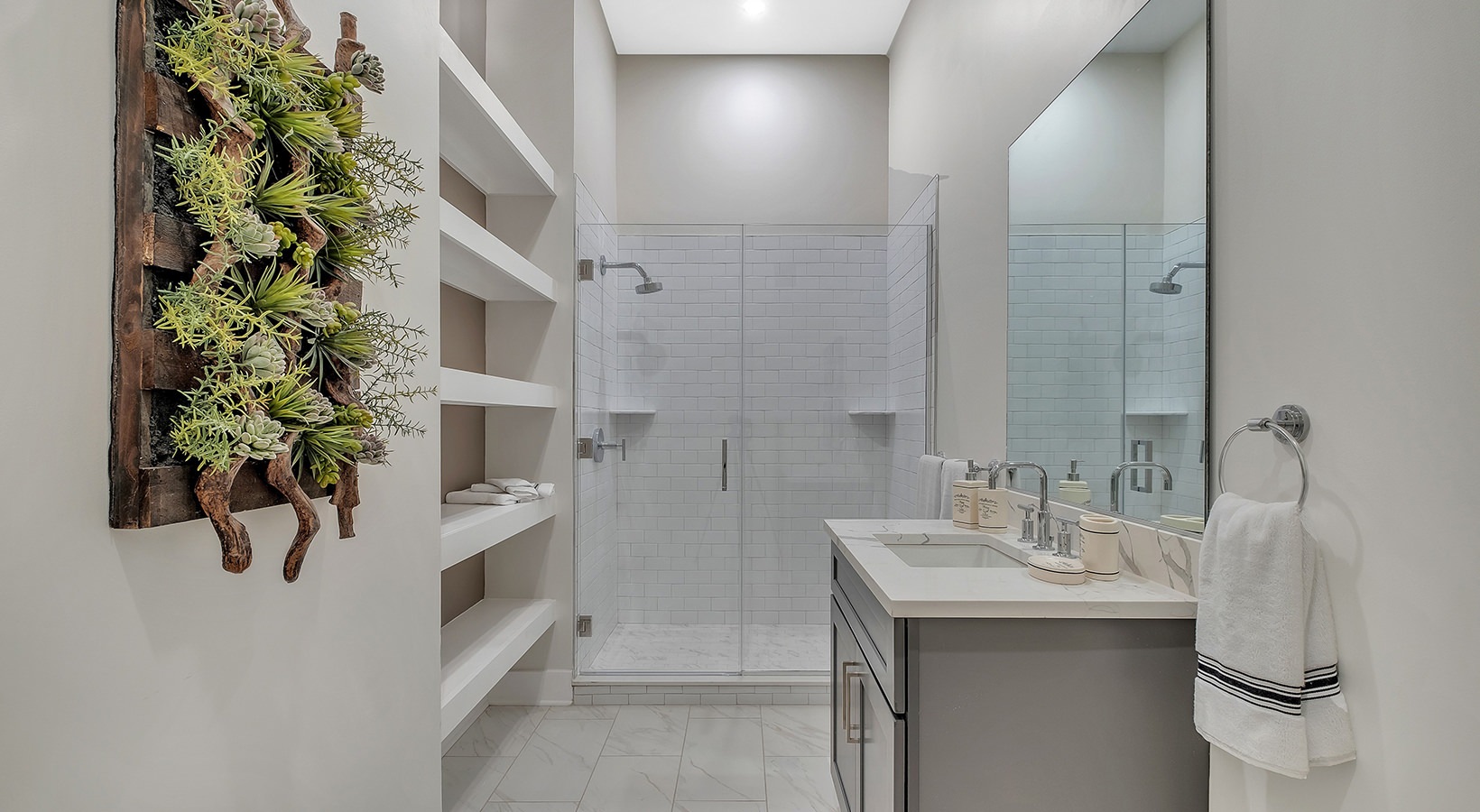 Designer Bathroom Model bathroom at our senior living apartments in Princeton, NJ, featuring white counters and a shower with a glass door.