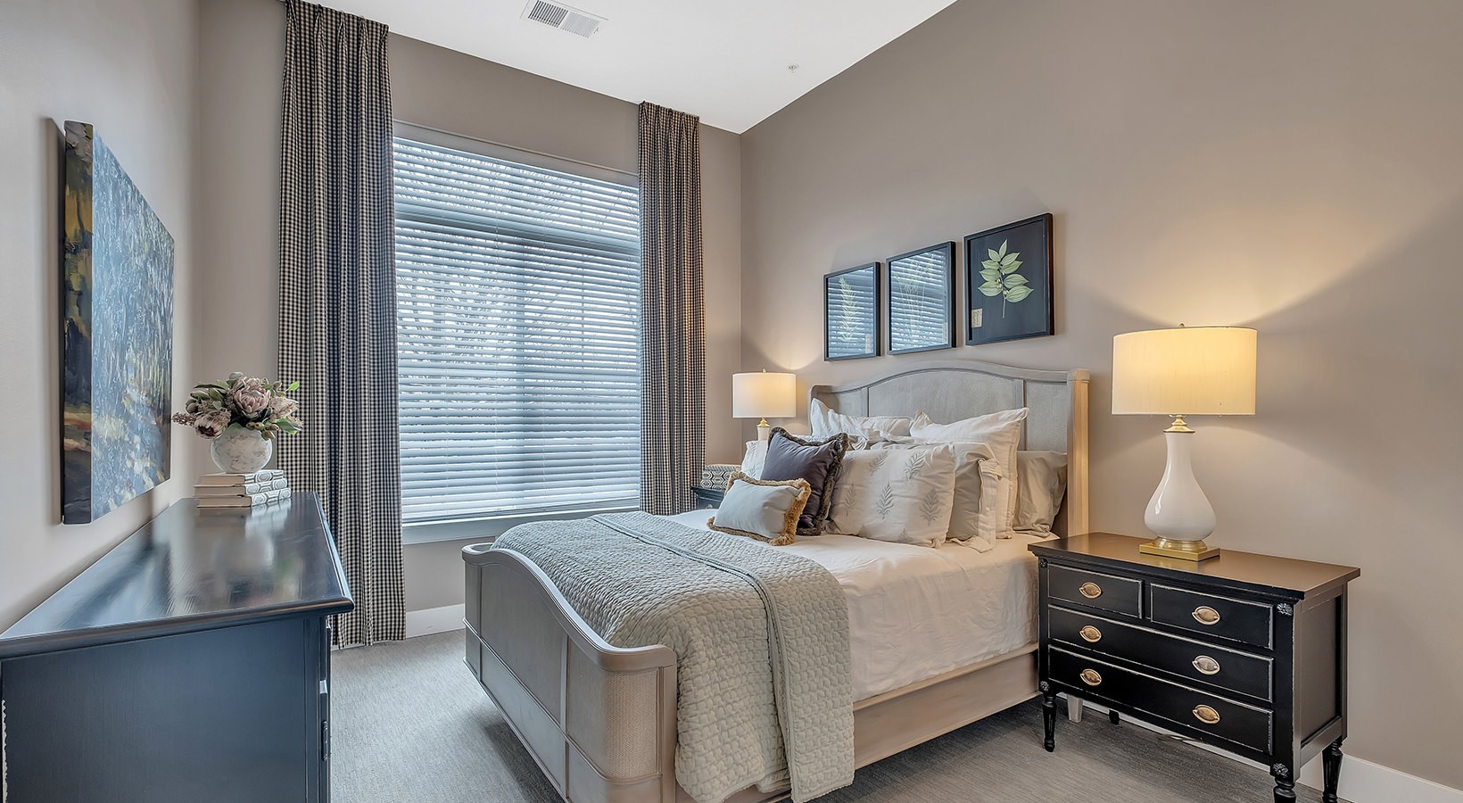 Spacious Bedroom Model bedroom at our senior living apartments in Plainsboro, NJ, featuring windows with blinds and a large bed.