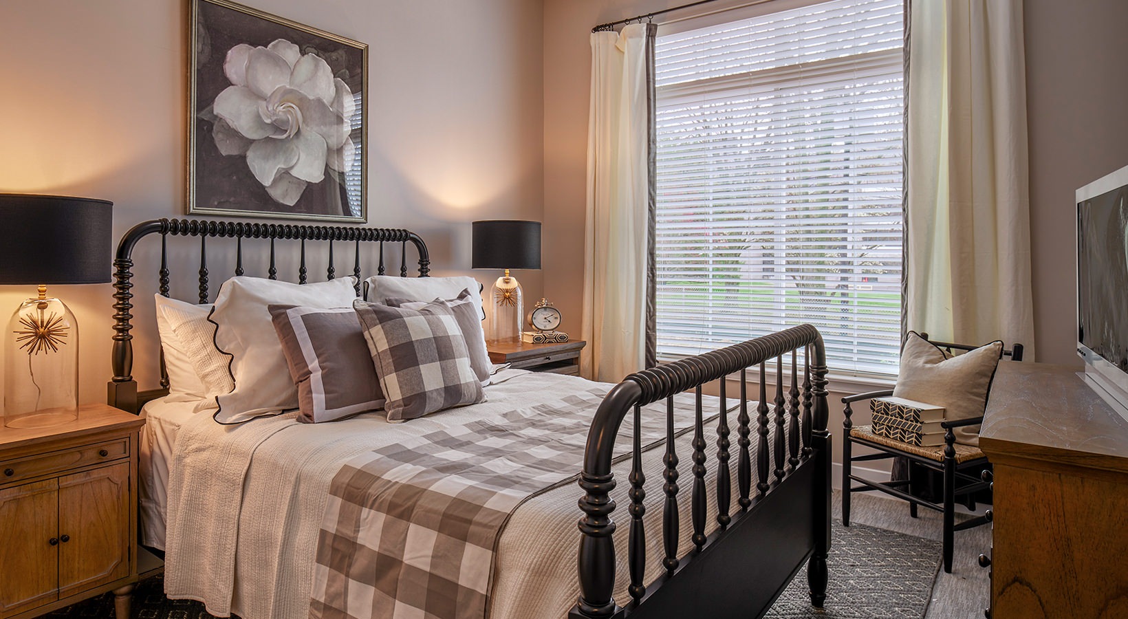 Spacious Bedroom Model bedroom at our senior living apartments in Plainsboro, NJ, featuring wood grain floor paneling and a large bed.